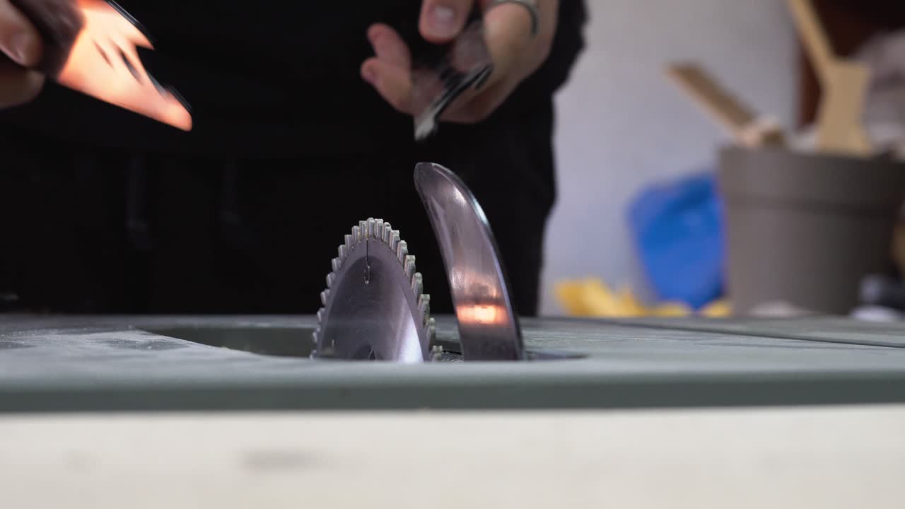Person removing table saw blade in a workshop setting with focus