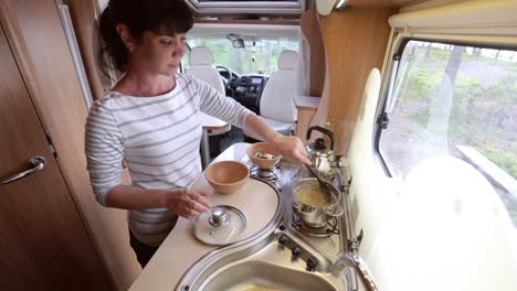 Woman-cooking-in-camper,-motorhome-interior