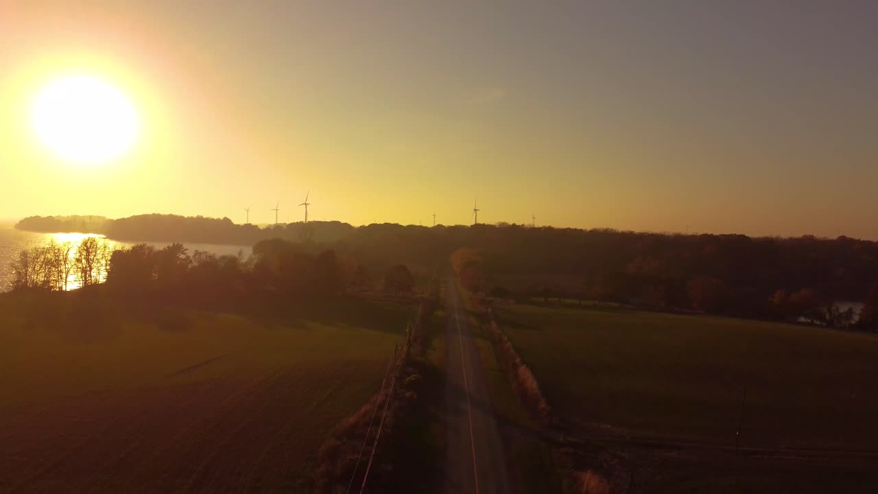 Freeway to a windmill farm during a big intense yellow sunset sky
