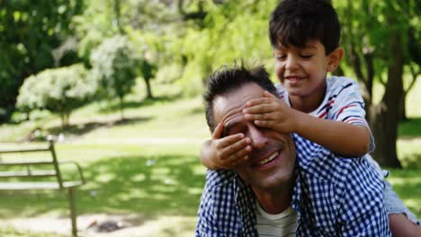 boy covering his fathers eyes in the park