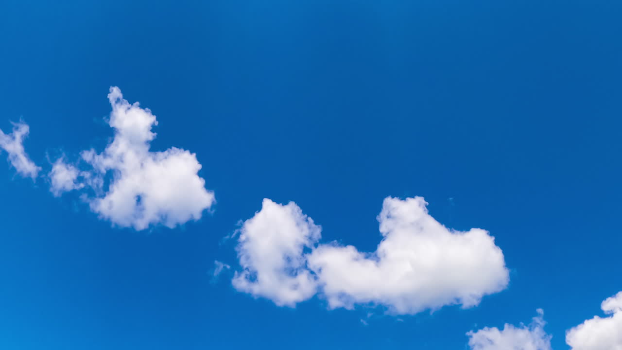 Lovely azure sky with little fluffy clouds quickly floating. Adorable summer weather. Low angle view. Timelapse.
