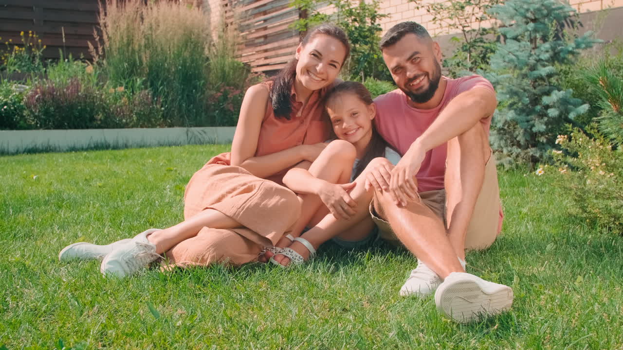 Delighted Family Hugging On Lawn In Summer