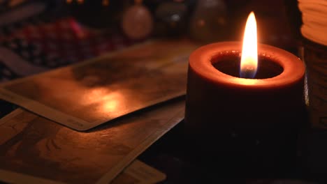 Fondo-De-Una-Mesa-De-Adivinos-Cubierta-De-Tela,-Con-Bolas-De-Cristal,-Piedras,-Cartas,-Libros-Antiguos-Y-Velas-Con-Llamas-Parpadeantes