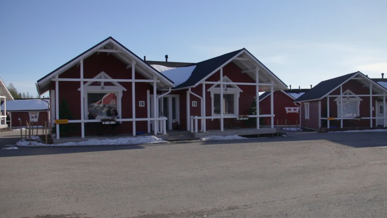Cozy red cottages under a clear winter sky in Santa Claus Holiday Village Rovaniemi Finland