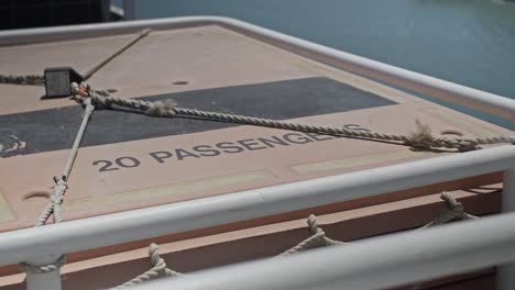 a locked rope tying down life raft on the back of a ferry with max 20 passengers sign on top