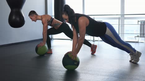 Women Doing Push-ups with Medicine Balls in Gym