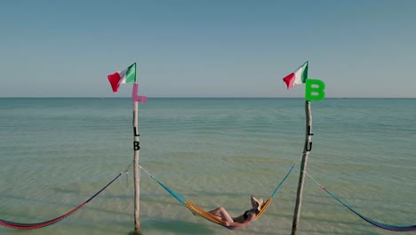 mujer turista con sombrero de paja tendido en hamacas de holbox, día soleado