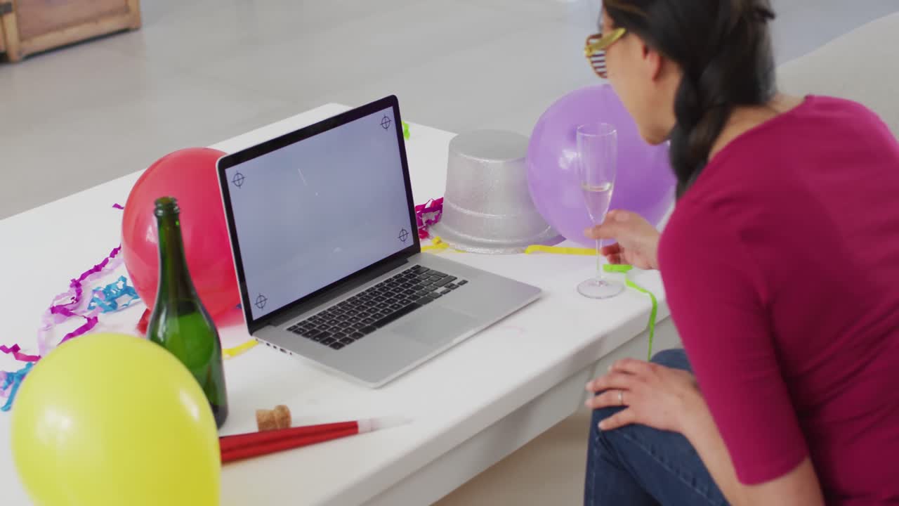 Happy asian woman with champagne making new year's eve video call on laptop with copy space