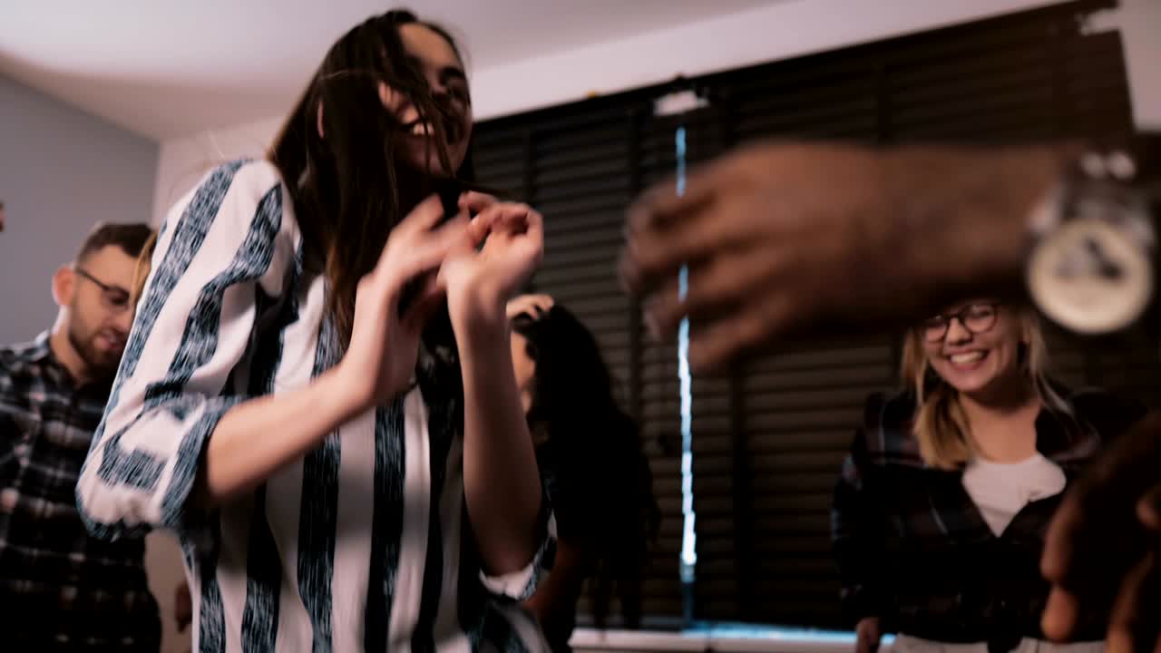 Successful young Caucasian businesswoman celebrating achievement with multiethnic friends at dance party slow motion