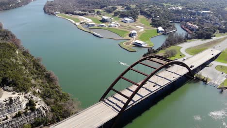 aerial austin pennybacker bridge - moving towards bridge set diagonally, pausing as bridge fills bottom right third of frame, pausing as boat on other side begins to take off leaving distinctive wake