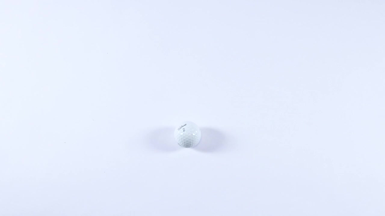 En golfbold ruller hen over en hvid overflade.