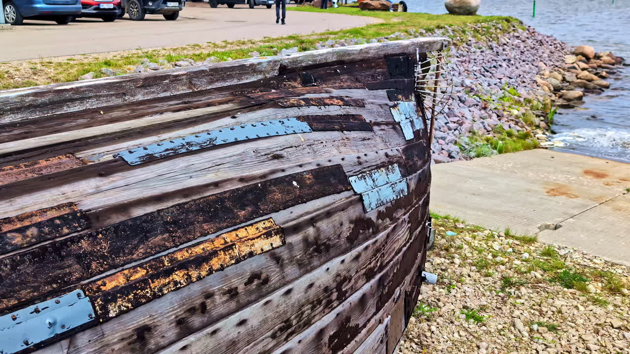 Closeup of an old wooden boat hull with metal patch repairs along a shore in Cesis. , Latvia