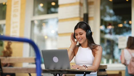 mujer joven trabajando en una computadora portátil en un café