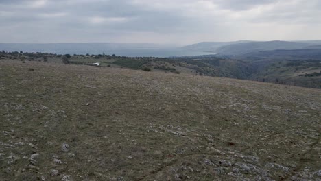 drone flyover aerial view of rocky terrain with rolling hills in distance, israel