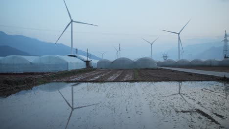 a large chinese windfarm located in the valley of sichuan located in between traditional chinese farms with farmers working