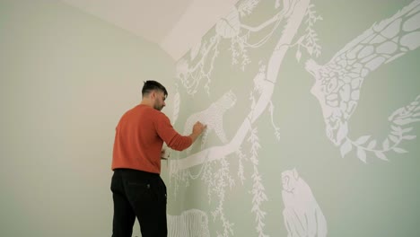 el artista está decorando las paredes con dibujos en la habitación de los niños. pintura de arte de las paredes en la casa nueva. trabajos de reparación.