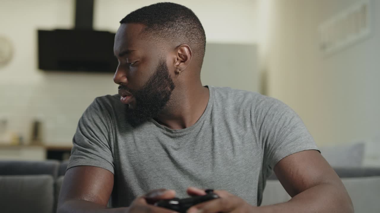 Koncentreret mand spiller spil i køkkenet. Frustreret fyr holder PlayStation.