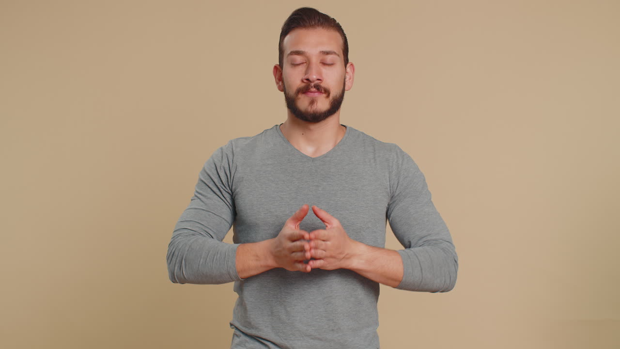 Young lebanese man breathes deeply eyes closed meditating with concentrated thoughts peaceful mind