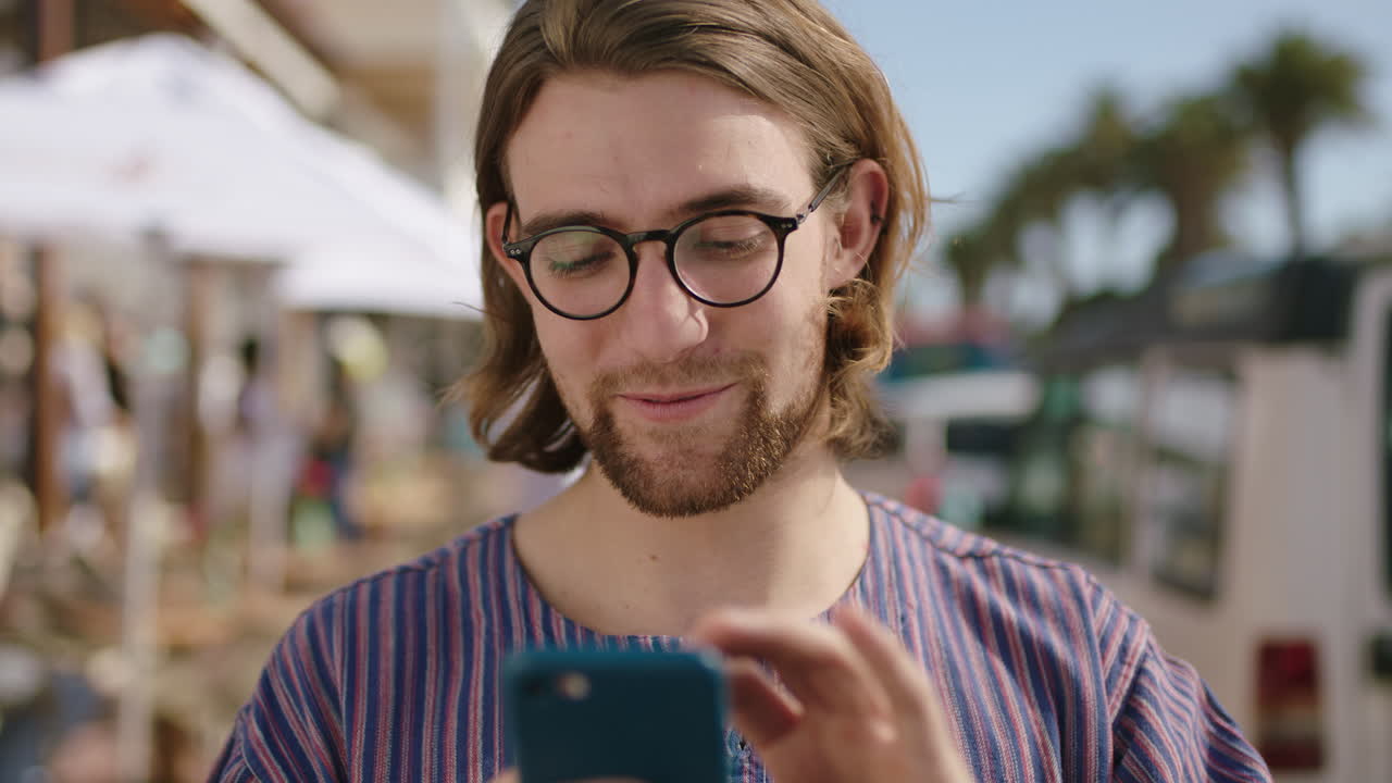 ritratto di un attraente uomo geek felice che invia messaggi usando il telefono