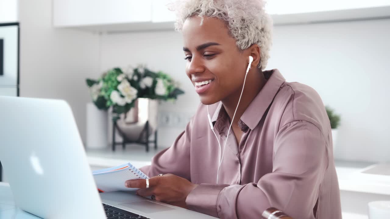 Giovane donna afroamericana felice che guarda un podcast video o un film sul laptop