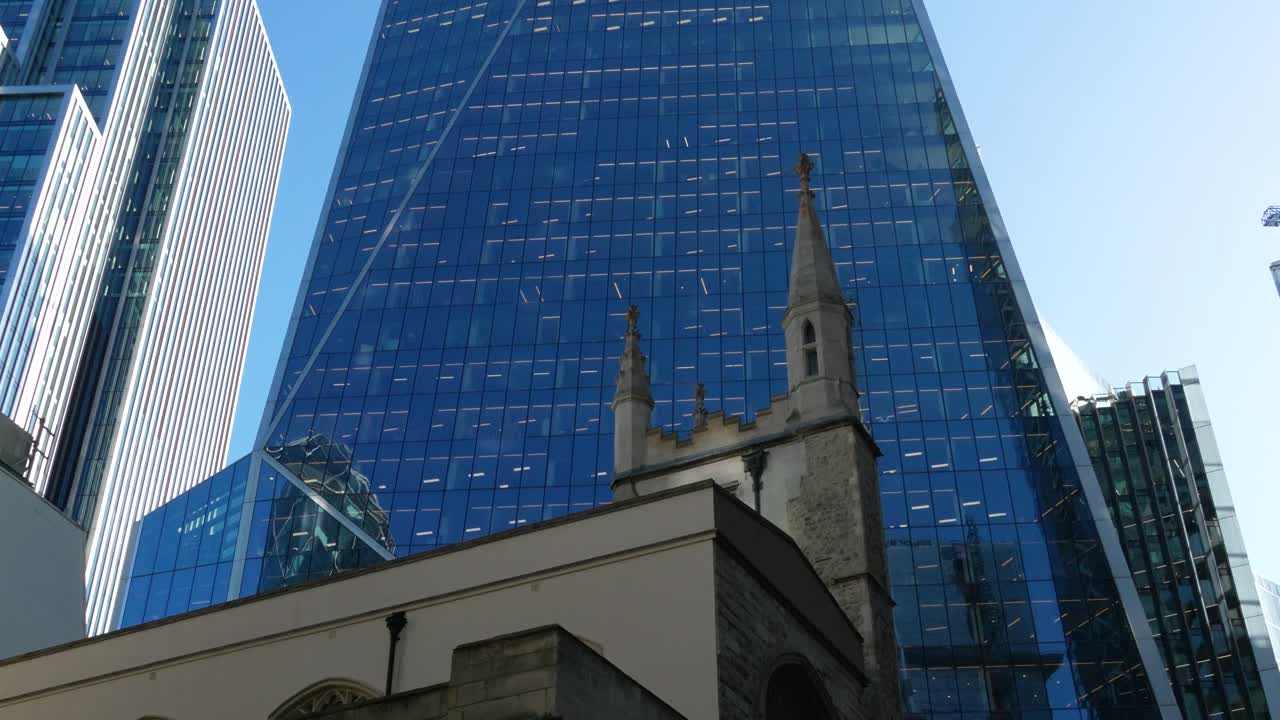 Contraste entre la arquitectura histórica de iglesias de piedra y los modernos rascacielos de cristal en la Ciudad de Londres. La escena destaca la fusión de patrimonio y desarrollo urbano contemporáneo