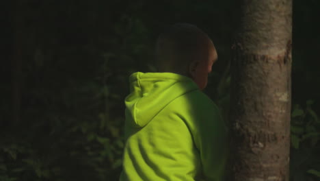 child walks across dark forest alone. little boy plays in night nature park on vacation. healthy kid explores wild wood walking in evening time