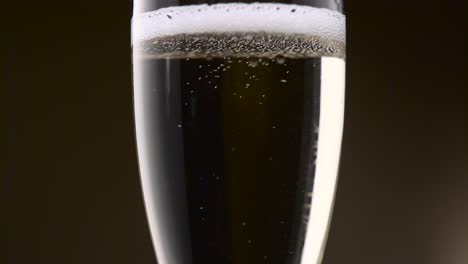 bubbles of champagne are intensely circling in a glass bubbles of festive champagne are intensely circling in a glass forming a foam then the soothing drink becomes transparent close up