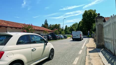 vehicles drive along a sunny street in cuneo