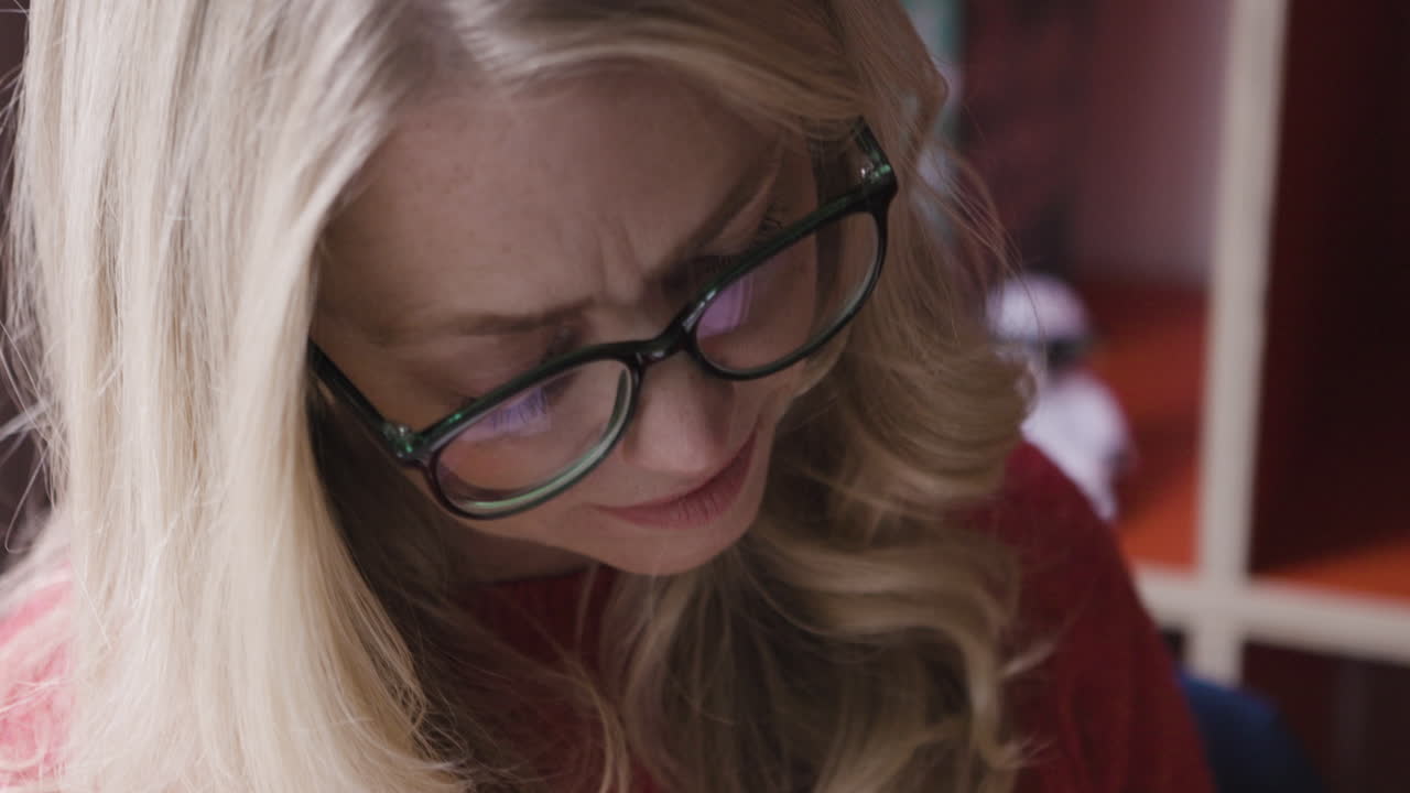Close-up of a woman in a red sweater reading a book