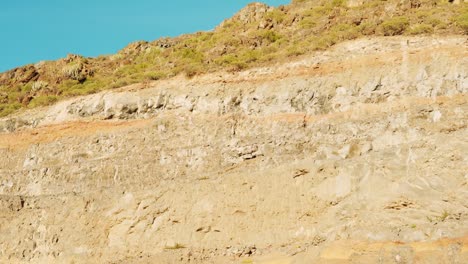 Detailed-view-of-volcanic-cliff-in-Tenerife-island-on-sunny-day,-tilt-up