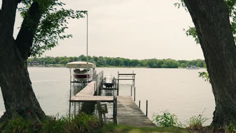 a dock with boats on a lake with a large boat moving in the background