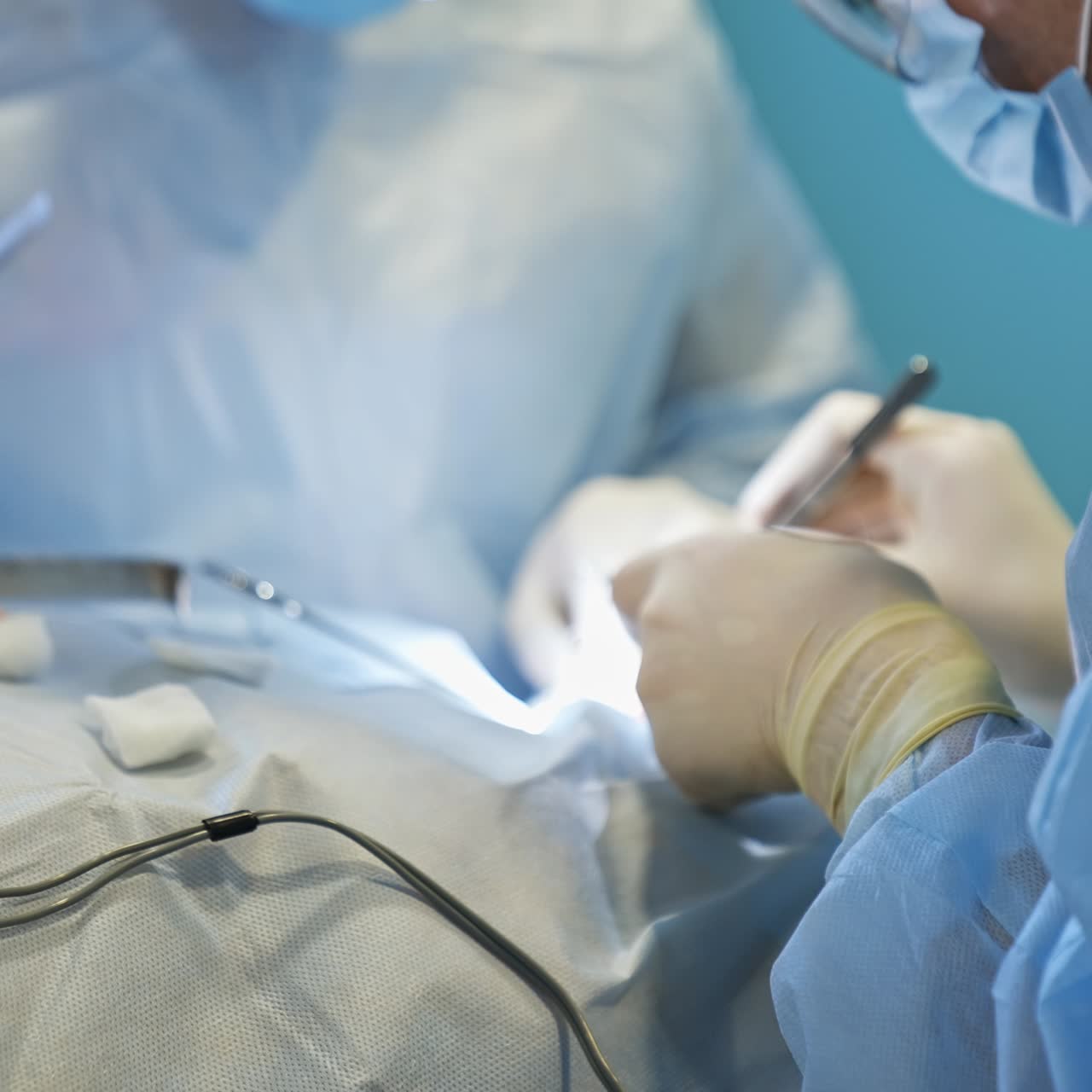 Nurse's hand in latex gloves holds the forceps with a surgical thread prepared for doctors. Unrecognized male surgeon drops his instrument and takes the forceps