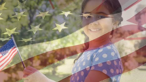 Animation-of-flag-of-america-blowing-over-smiling-girl-in-park-holding-usa-flag