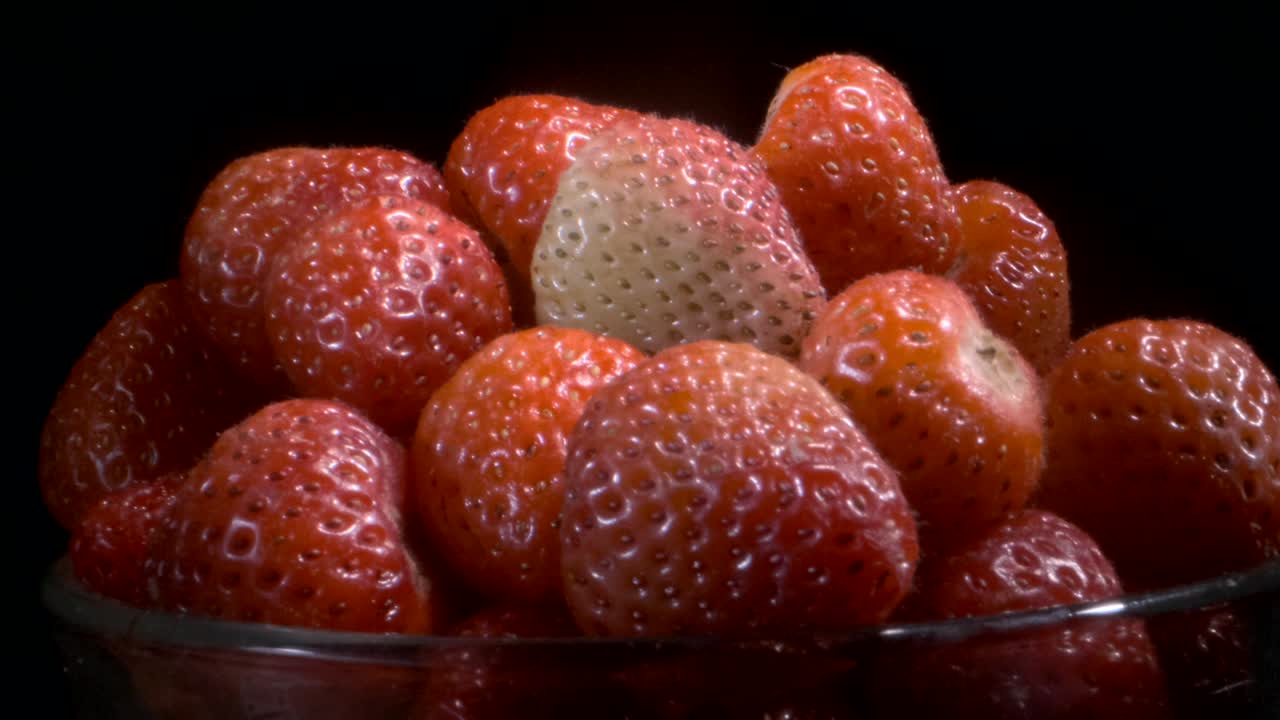 흑색 바탕에 은 스크린에서 빨간 딸기를 회전합니다. 카메라 회전 360도, 클로즈업.
