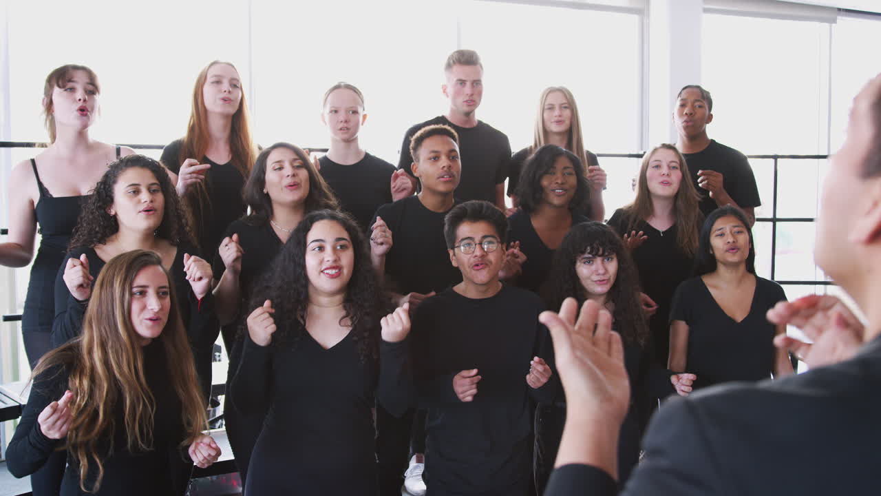 estudiantes masculinos y femeninos cantando en el coro con el maestro en la escuela de artes escénicas