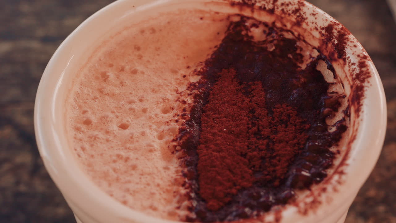 Primo piano di una ricca superficie di cioccolata calda o caffè cosparsa di cacao in polvere
