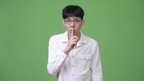 입술에 손가락을 은 젊은 아시아 사업가