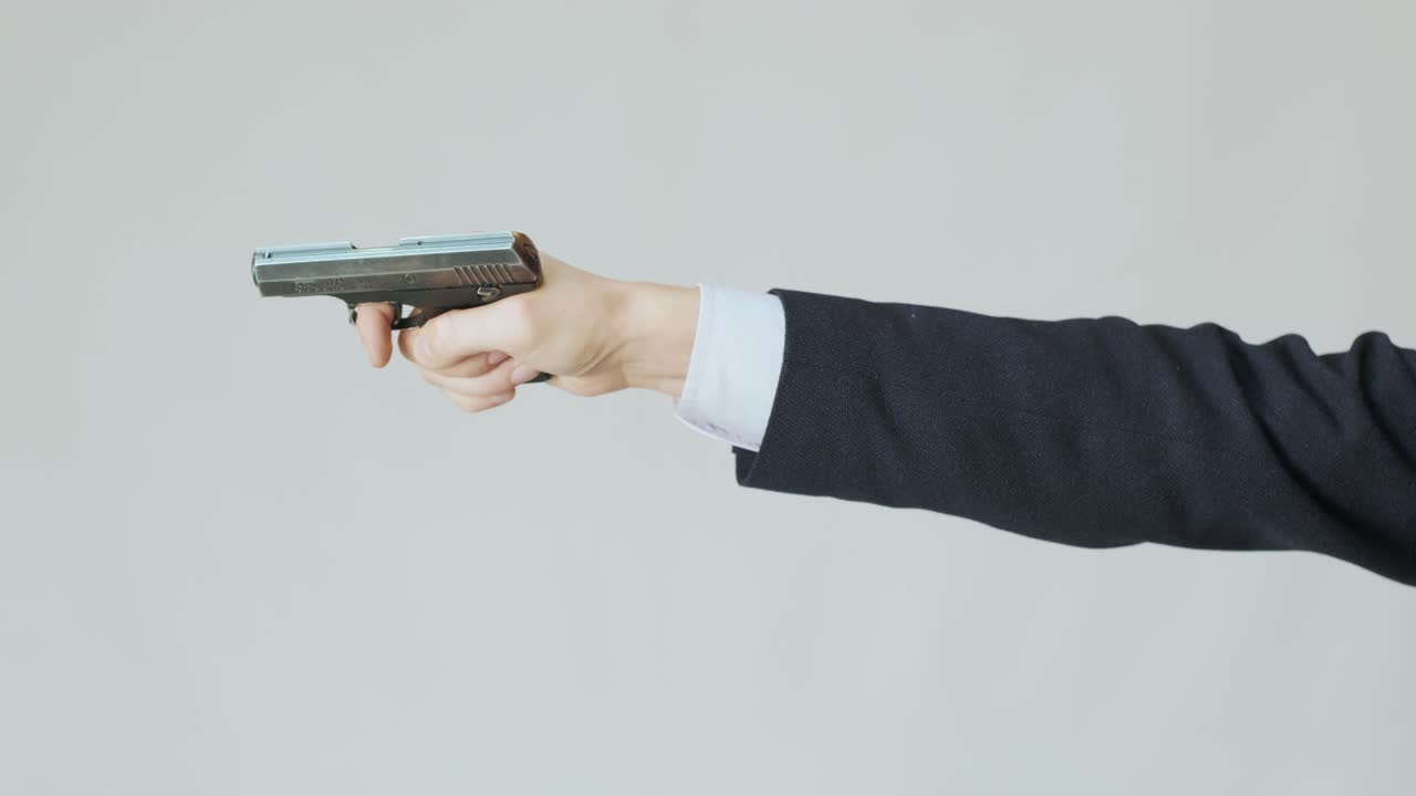 손에 총을 든 재을 입은 사업가 한 명이 볼트를 다시 충전하고 총을  준비하고 있습니다.