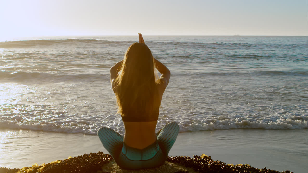Donna in forma che pratica yoga in spiaggia 4k