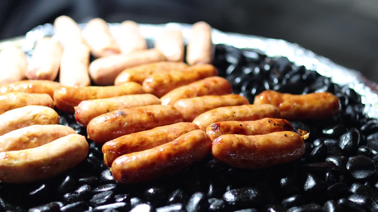 Sizzling sausages cooking evenly on a grill