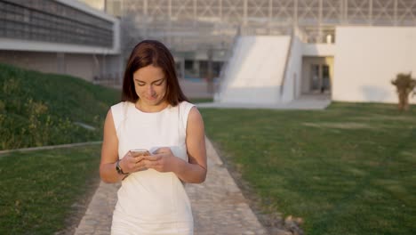 vista frontal de una joven feliz enviando mensajes en su teléfono inteligente.