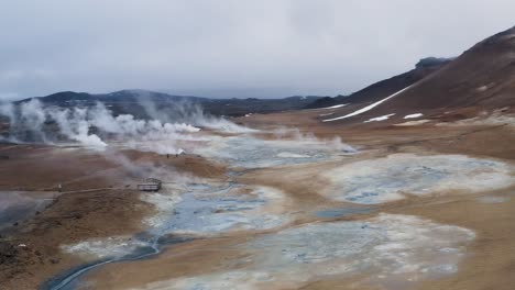 aerial view above geothermal area with boiling mud pools in blue color during cloudy day in iceland