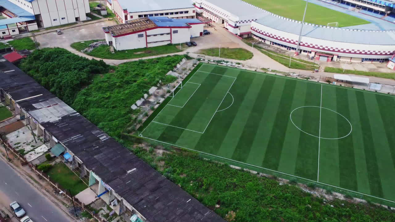 High angle pan from football field to a calm street near a stadium in the city of Abuja, Nigeria