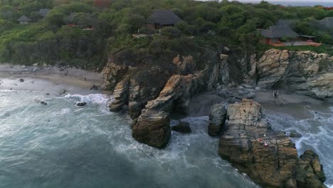 aerial shot of rock formation and houses in zicatela beach, puerto escondido, oaxaca