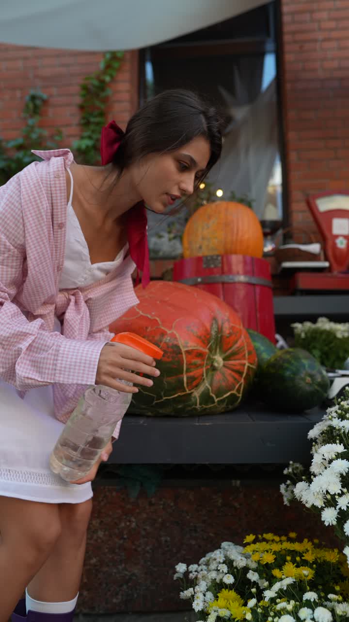 여인 이 호박  에서 식물 에 물 을 주고 있다