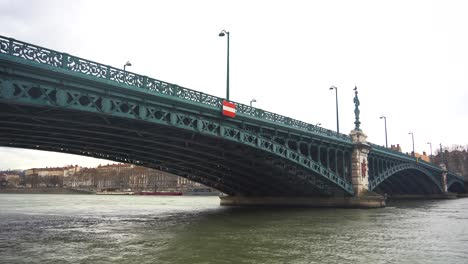 Steel-Bridge-with-Arches-Spanning-Lyon's-Quiet-Rhone-River,-Enhancing-the-Beautiful-Cityscape-of-Historic-Lyon,-France