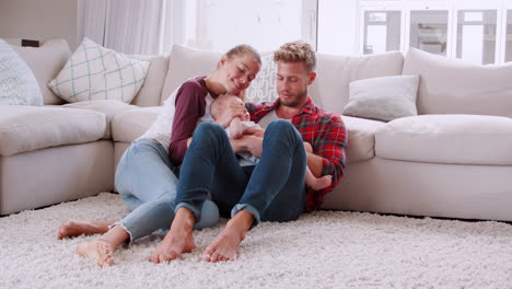 Young-couple-sitting-on-the-floor-at-home-with-their-baby