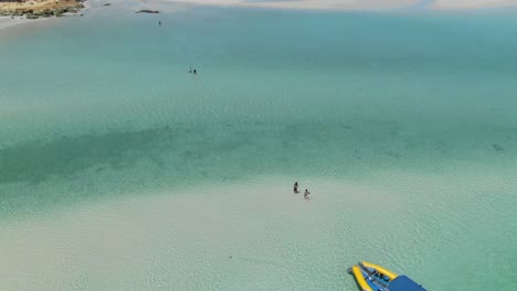 avance aéreo sobre turistas caminando en aguas poco profundas y transparentes, playa whitehaven