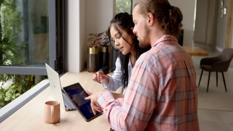 A-diverse-couple-in-travel-planning-at-home-using-a-tablet-and-laptop