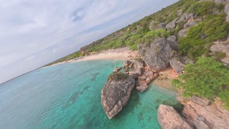 Aerial-fpv-flight-along-sandy-beach,-coral-reef-,-parking-boats-and-exotic-trees-in-summer---BAHIA-DE-LAS-AGUILAS,Dominican-Republic